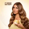 Model with long, glossy waves holding a jar of Honey Gloss Ceramide Therapy Hair Mask