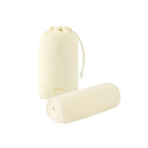Cream-coloured Gisou Honey Gloss Microfiber Hair Towel, rolled, beside its drawstring pouch