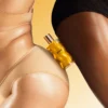 Honey Infused Body Oil bottle resting on glowing skin