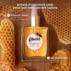 Gisou Honey Infused Hair Oil bottle with dropper – view 3 Honey Infused Hair Oil bottle resting on honeycomb from the Mirsalehi Bee Garden