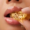 Close-up of glossy lips biting into golden honeycomb